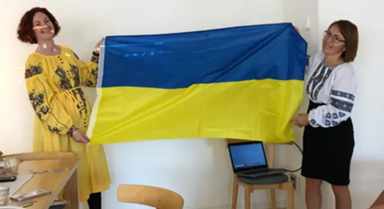 Två kvinnor håller upp en Ukraina-flagga